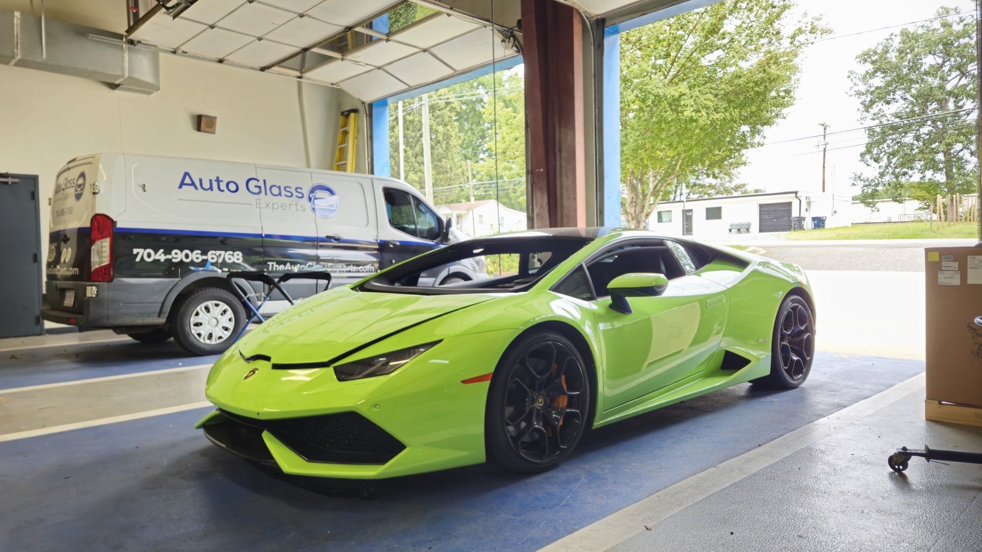 Bright green sports car parked in a garage, with a van in the background.