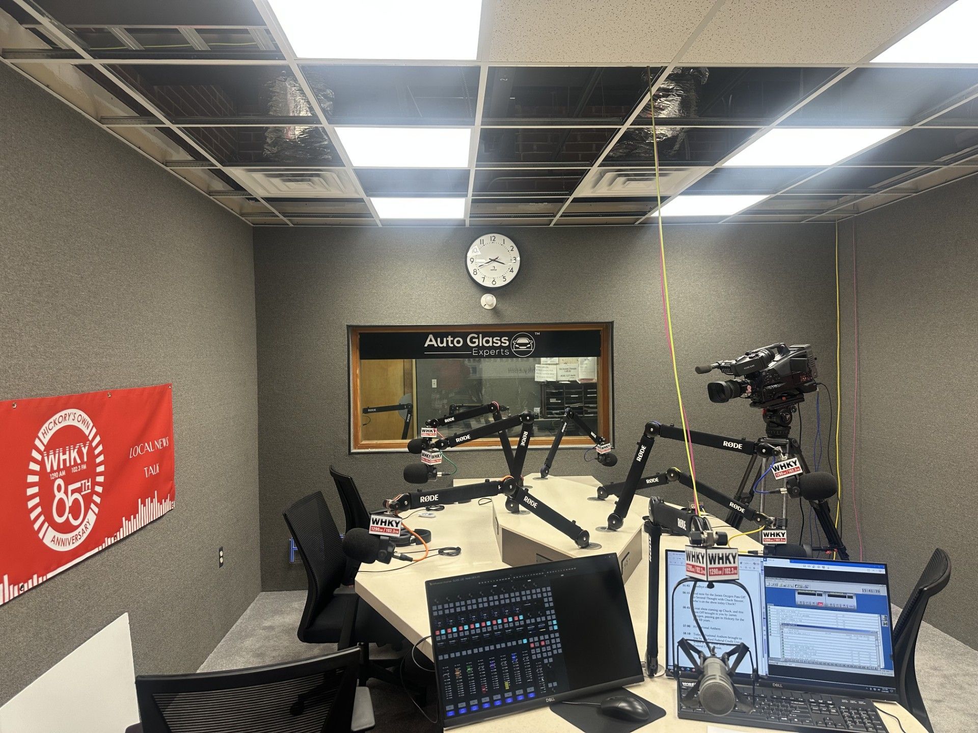Podcast studio with microphones, laptops, camera, and acoustic walls in a gray room