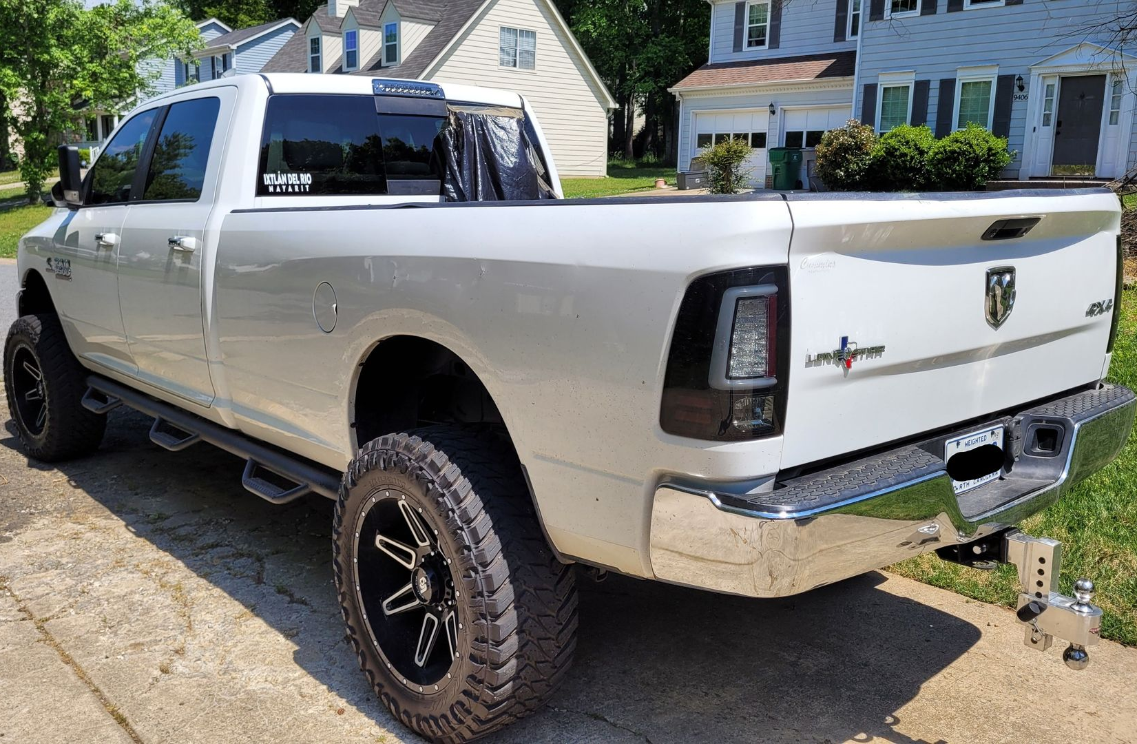 Silver pickup truck parked in a driveway, rear three-quarter view, with black wheels and chrome bumper