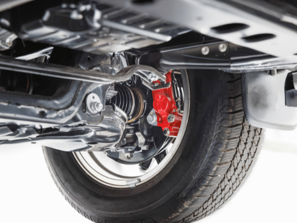 Car wheel and suspension with red brake caliper under the car chassis
