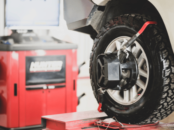 Car wheel on a balancing machine in an auto repair shop, with a red machine in the background