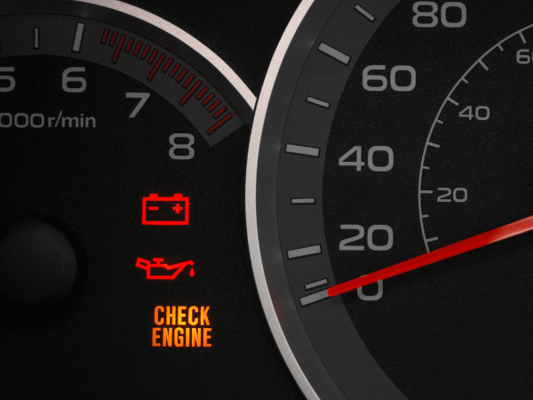 Car dashboard gauges with glowing battery, oil, and check engine warning lights