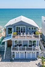 Blue beach house with ocean view, balconies, and garage doors.