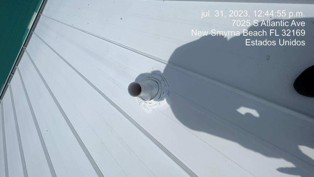 White metal roof with a pipe fitting, under a blue-green edge, in New Smyrna Beach, FL.