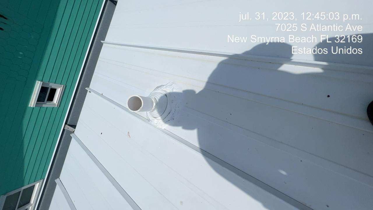 White metal roof with a vent pipe and shadow of the photographer, location: New Smyrna Beach, FL.