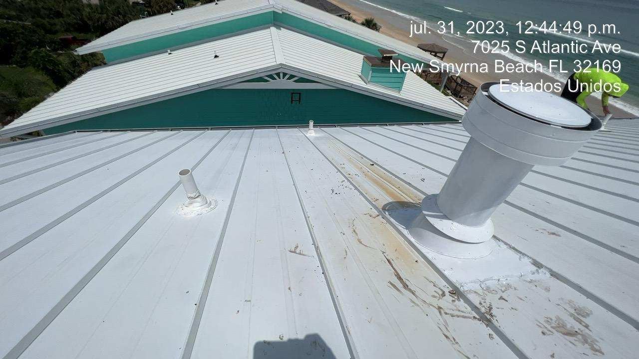 White rooftop with teal trim, near the ocean. Vent pipe and other equipment are visible.