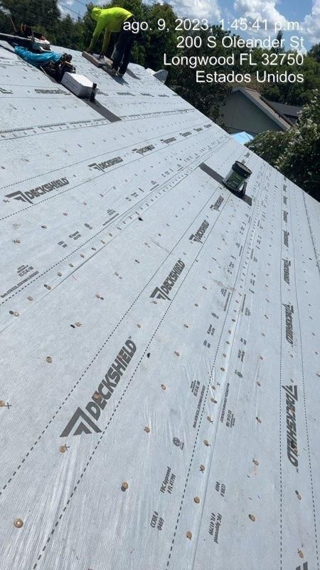 Roofers installing roofing material, Longwood FL. Gray material with black text.