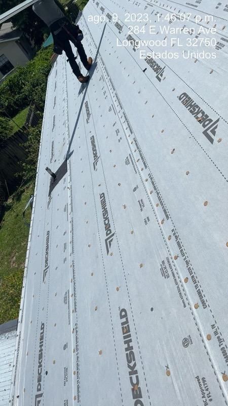 Roofer on a roof installing roofing underlayment, text: 