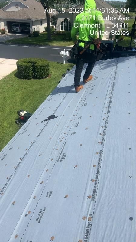 Roofer in neon green walks on new roof with underlayment in Clermont, FL.