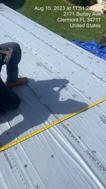 Person hammering on a roof with Clermont, FL address visible, along with a measuring tape.