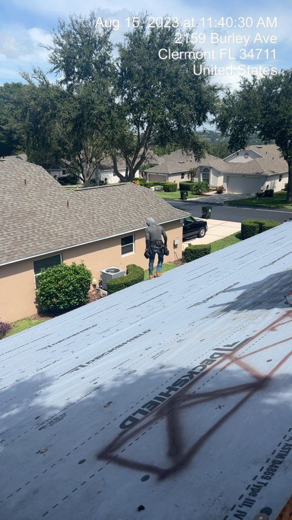 Rooftop view of residential neighborhood in Clermont, FL, with houses and trees under a partly cloudy sky.