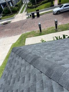 View of a dark gray shingled roof with a street in the background.