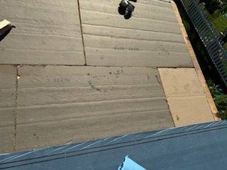 Roof insulation being installed on a wooden structure, with tools visible.