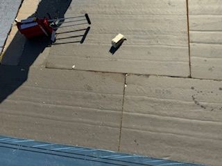 Overhead shot of a gray concrete surface with a toolbox and a small beige object on it.