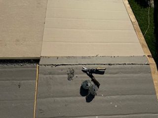 Overhead view of a deck being built. Concrete tiles are laid. Tools and adhesive are visible.