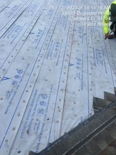Roofer installing synthetic underlayment on a roof in Clermont, FL.