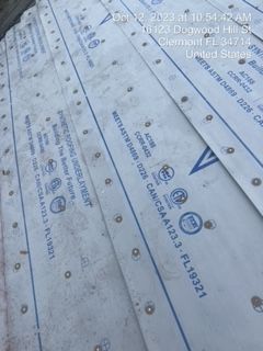 Close-up of overlapping white roofing material with rivets and printed text.