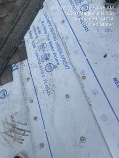 Synthetic roofing underlayment on a roof with visible markings and labels, possibly during installation.