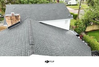 Gray shingle roof of a house with a brick chimney, seen from above.