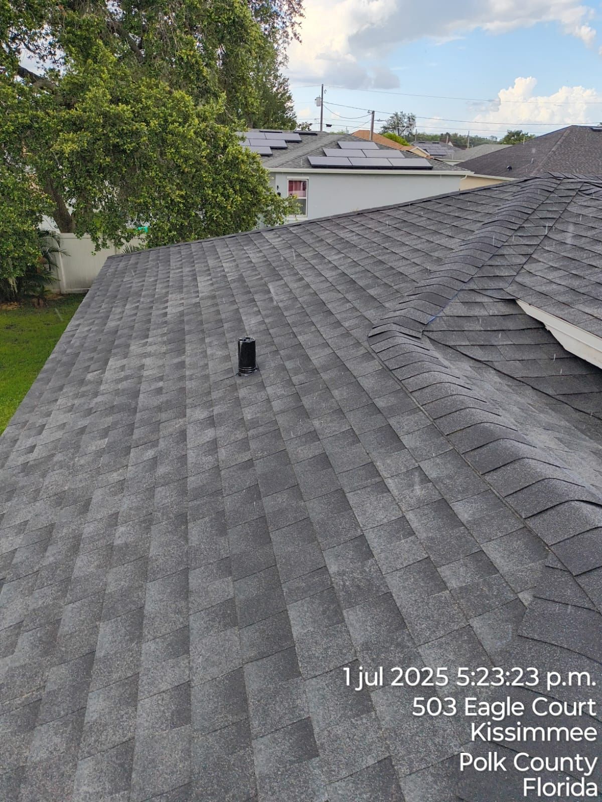 View of a dark gray shingle roof on a house in Kissimmee, Florida, with a vent pipe visible.