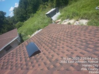 View of a brown roof with a skylight, hillside in background. Text: 3555 East Johnson Avenue, Haines City, Florida.