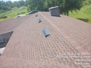 Brown asphalt shingle roof with skylights and a chimney. Location is 3555 East Johnson Avenue, Haines City, Florida.