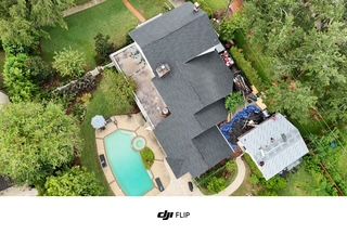 Aerial view of a house with a pool, surrounded by trees and greenery.