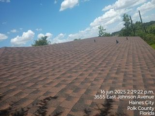 Brown shingled roof under a blue sky with clouds, taken in Haines City, Florida.