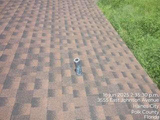 Roof with vent pipe, brown shingles, text overlay: 3555 East Johnson Avenue, Haines City, Florida.