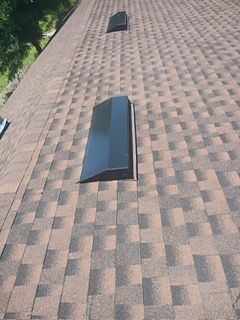 Brown shingled roof with two black vents.