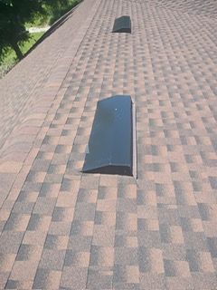 Brown asphalt shingle roof with two black vents.