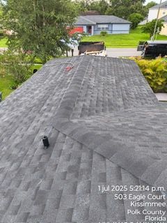 Rooftop view of a Kissimmee, Florida home with dark gray asphalt shingles. Date and address are in the corner.