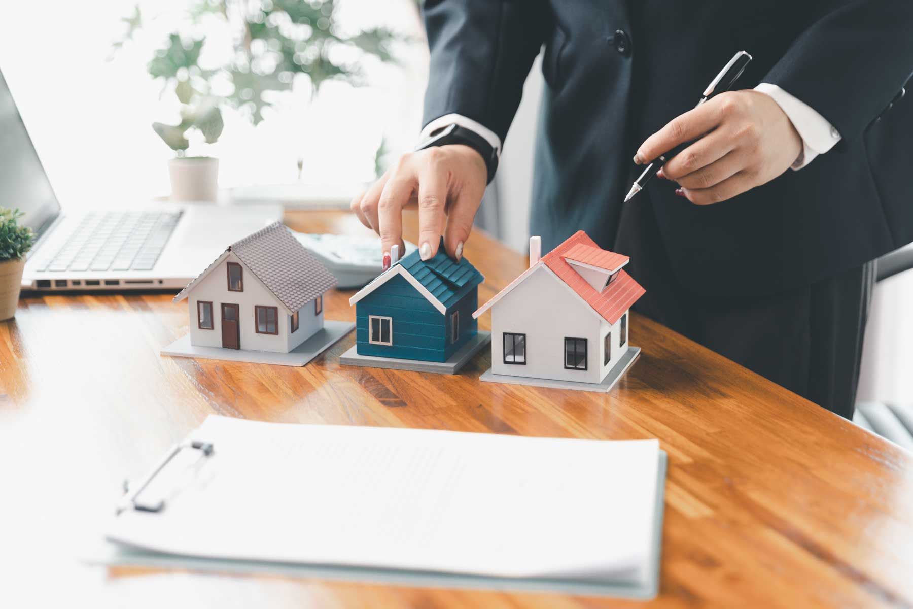 Forretningsmand placerer modelhuse på et skrivebord under et ejendomsmøde
