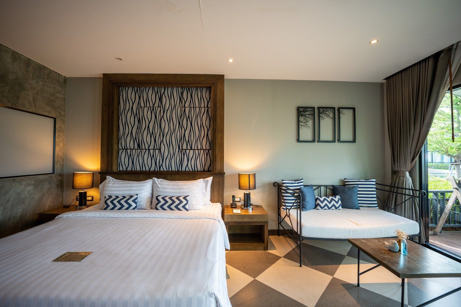 Hotel room with king bed, sofa, wood furnishings, and checkered floor.