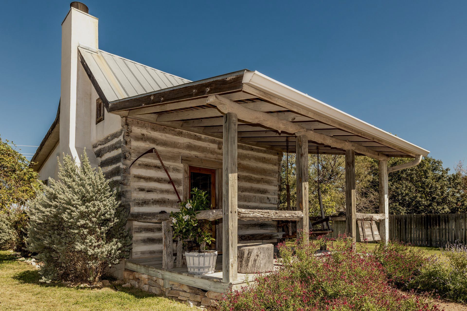 A small log cabin with a porch and a chimney.