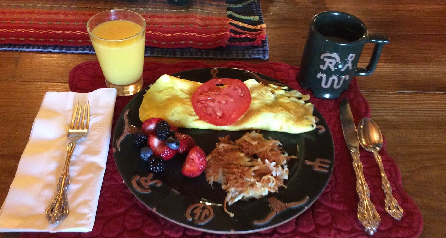 A plate of food and a cup of orange juice on a table.