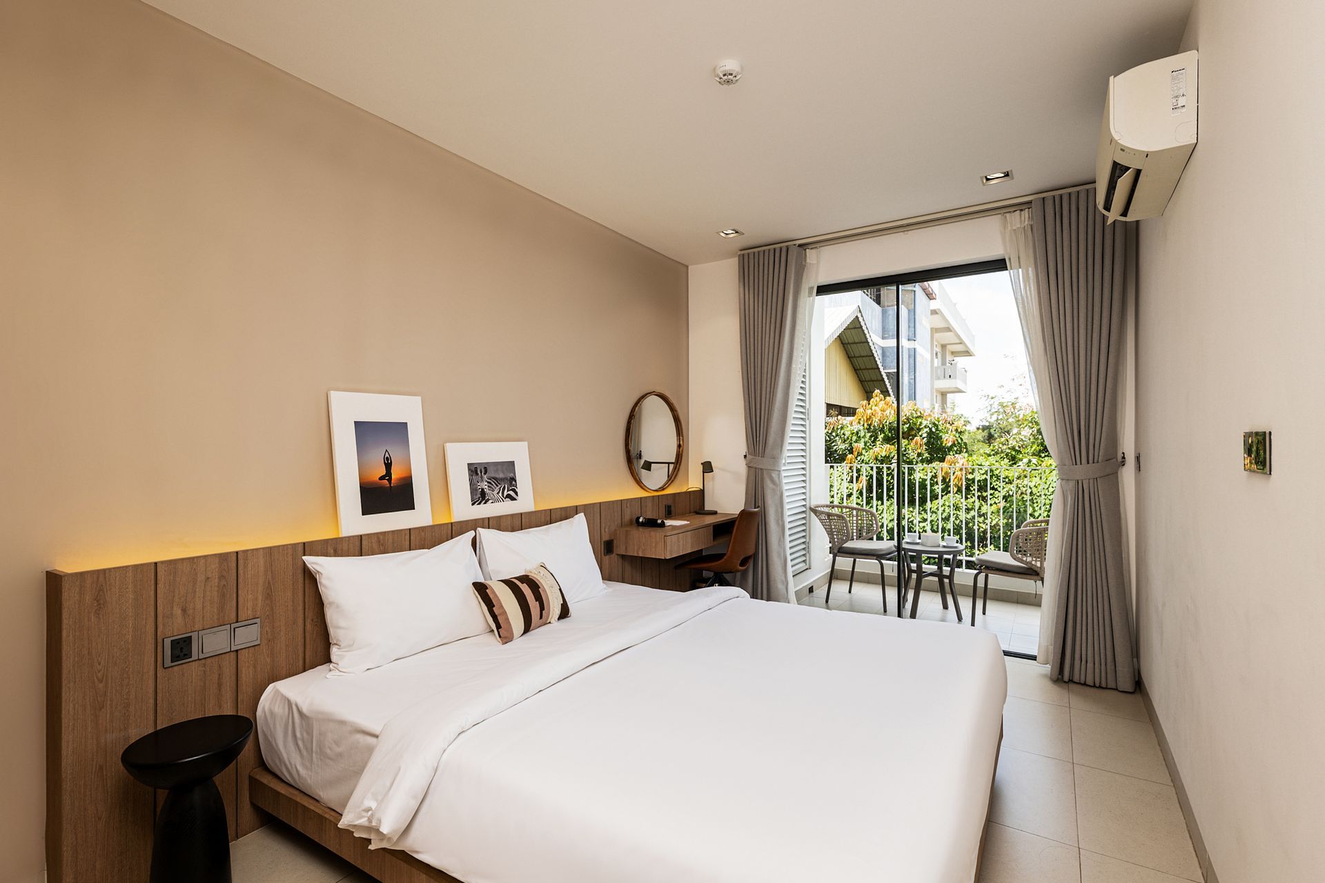 Bright hotel bedroom with a large bed, balcony view, and neutral decor