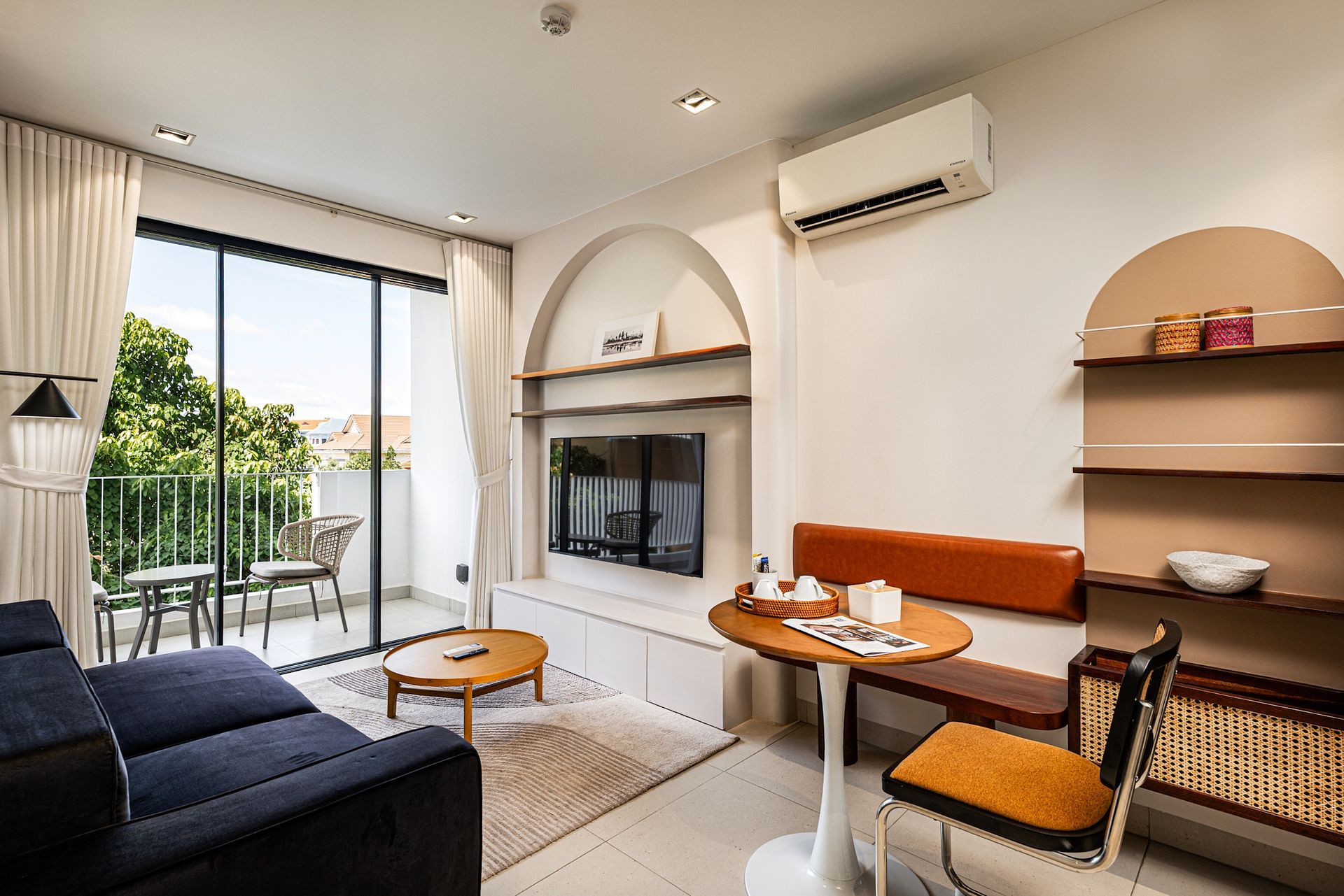 Bright living room with sofa, coffee table, fireplace, arched alcove, and balcony view