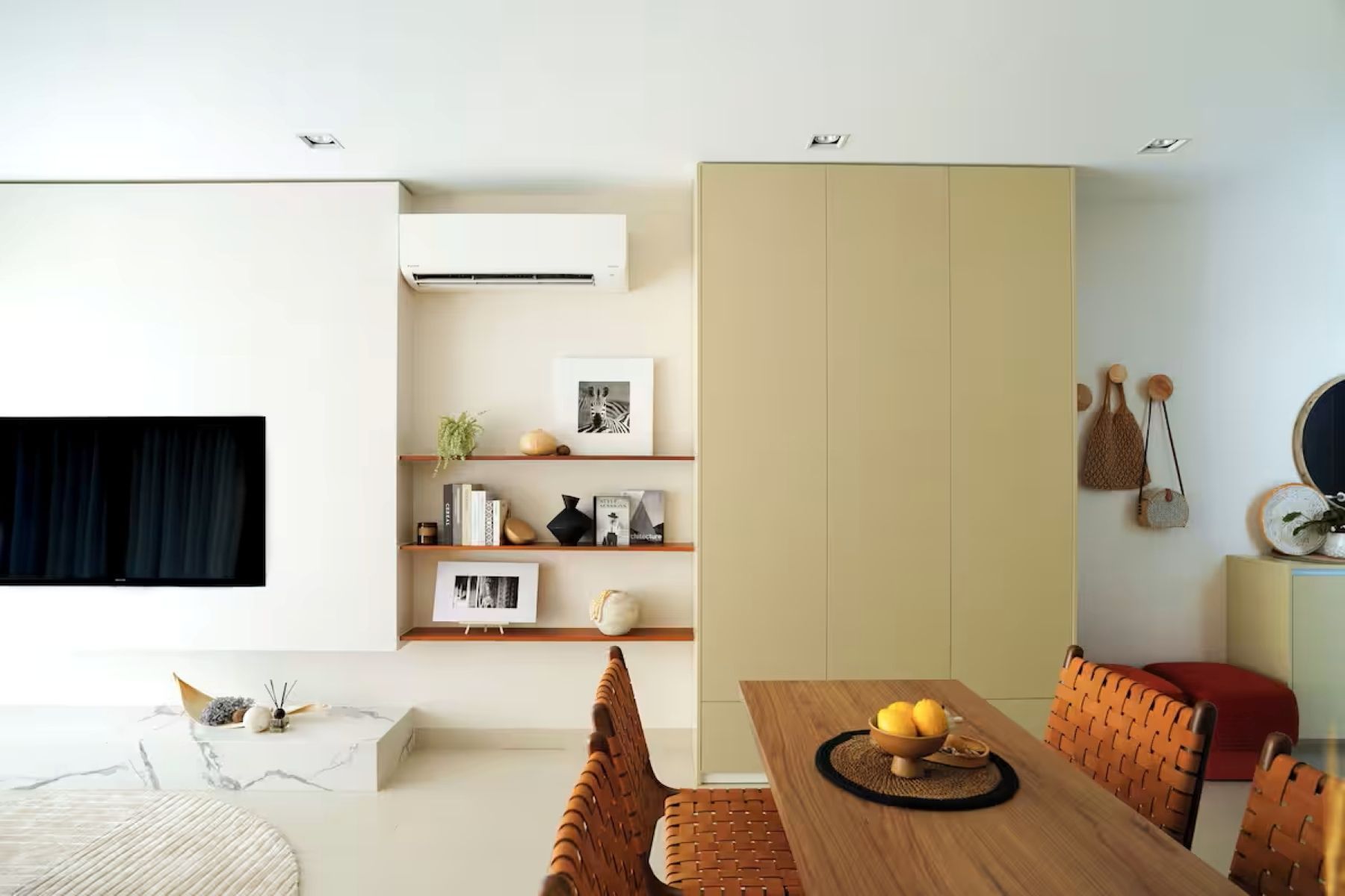 Modern living-dining room with white walls, beige cabinets, wood table, and orange chairs