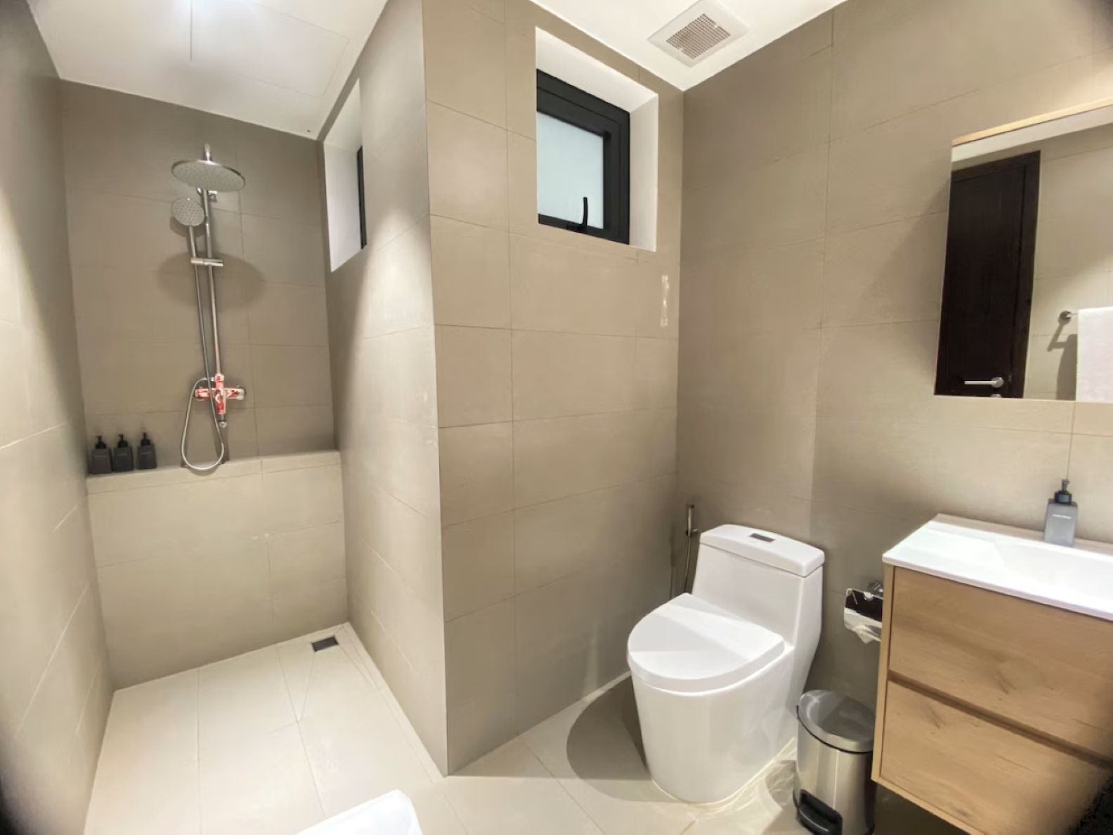 Modern bathroom with walk-in shower, toilet, and sink in beige and white tiles