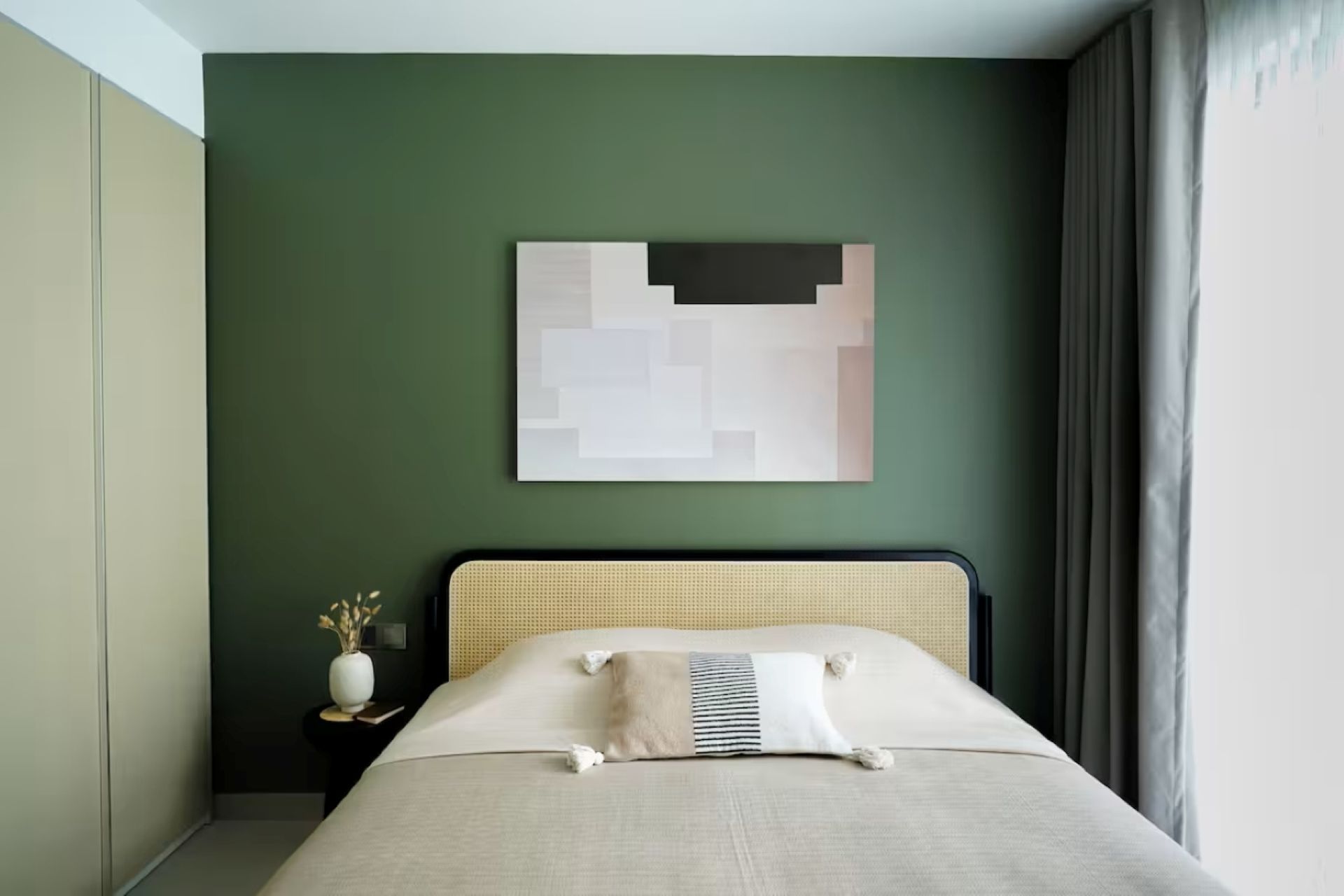 Minimal bedroom with green accent wall, bed, side table, and abstract wall art