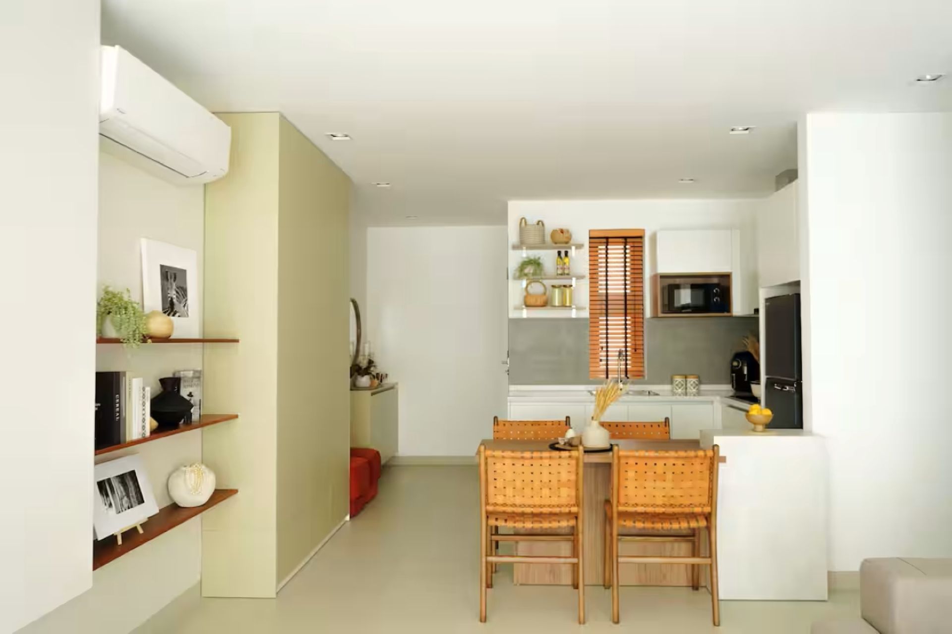 Bright minimalist kitchen and dining area with wooden table, chairs, white cabinets, and shelves