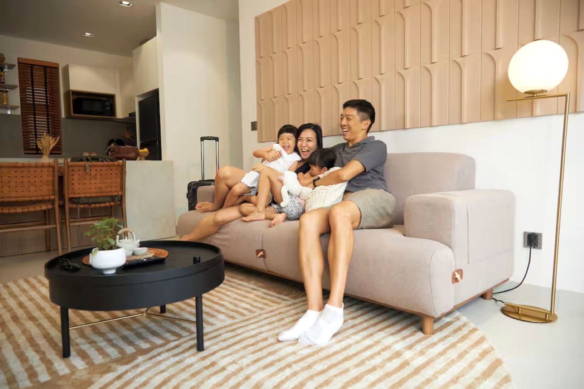 Two people relaxing on a beige sofa in a modern living room with a coffee table and floor lamp