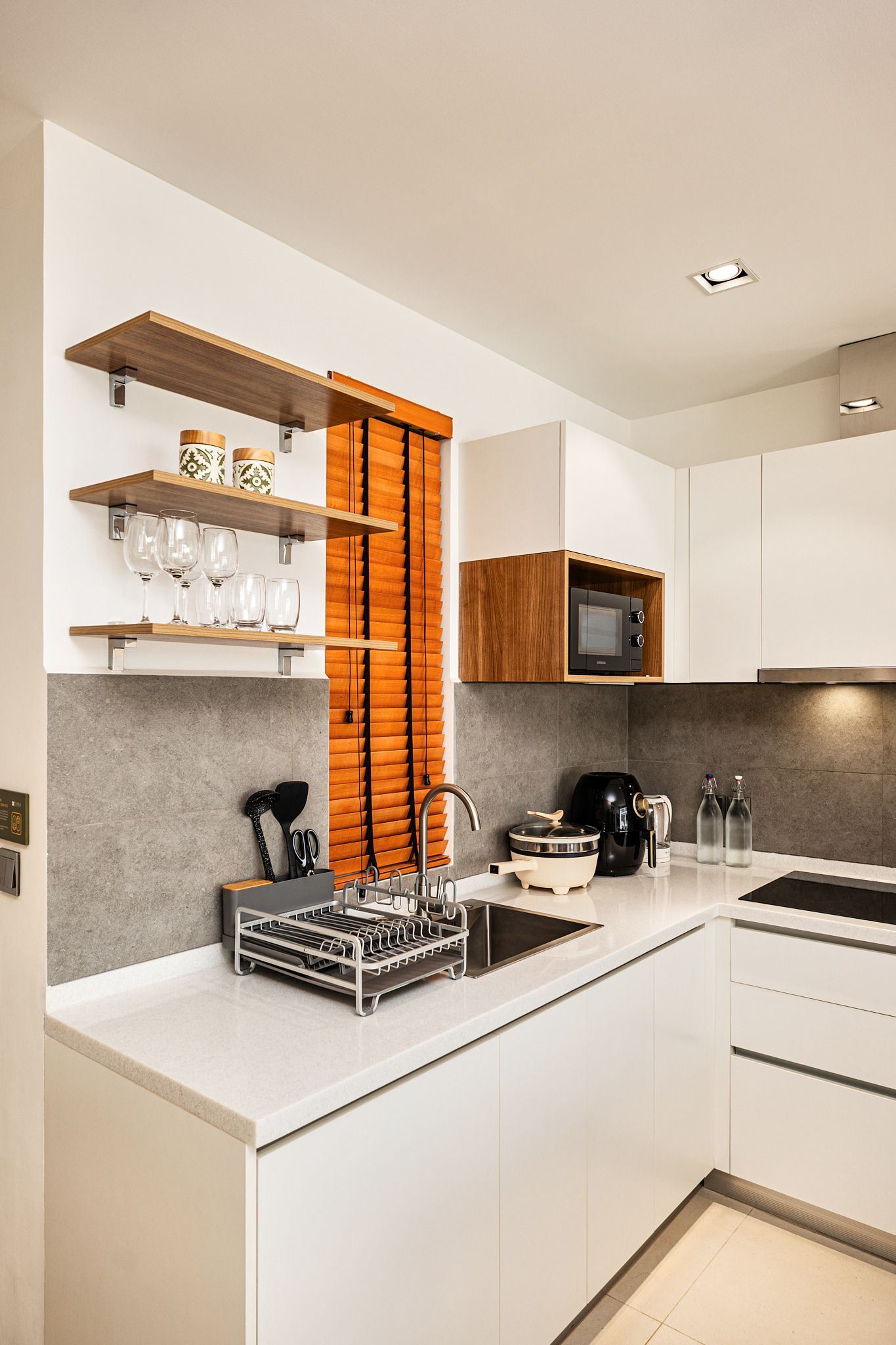 Modern white kitchen with black countertops, open shelves, and stainless steel appliances