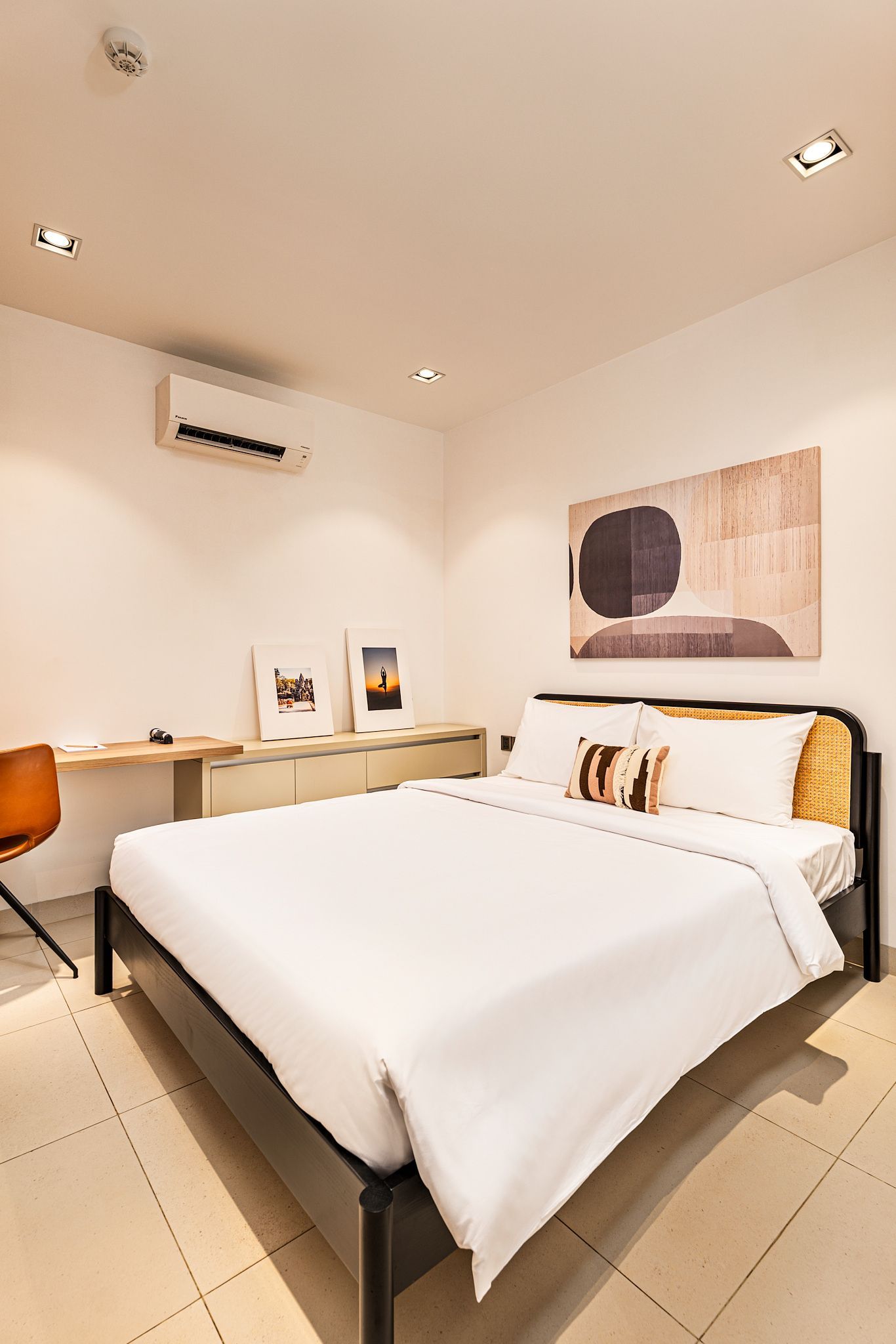 Minimalist bedroom with a large white bed, desk, and warm ceiling lights