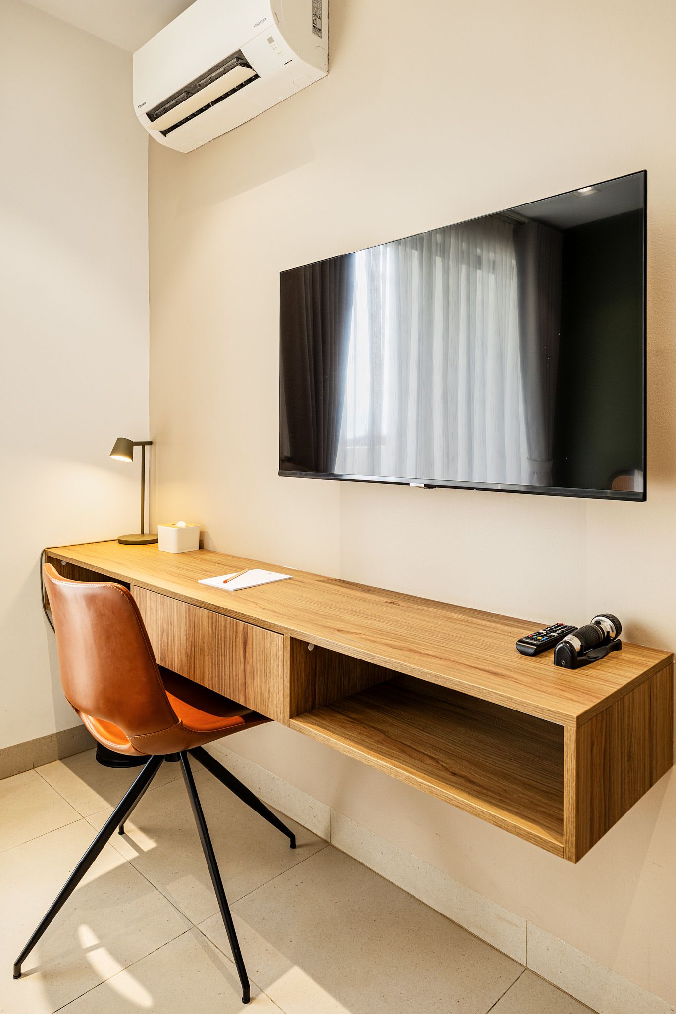 Modern living room with wall-mounted TV, floating shelves, air conditioner, and beige built-in cabinets