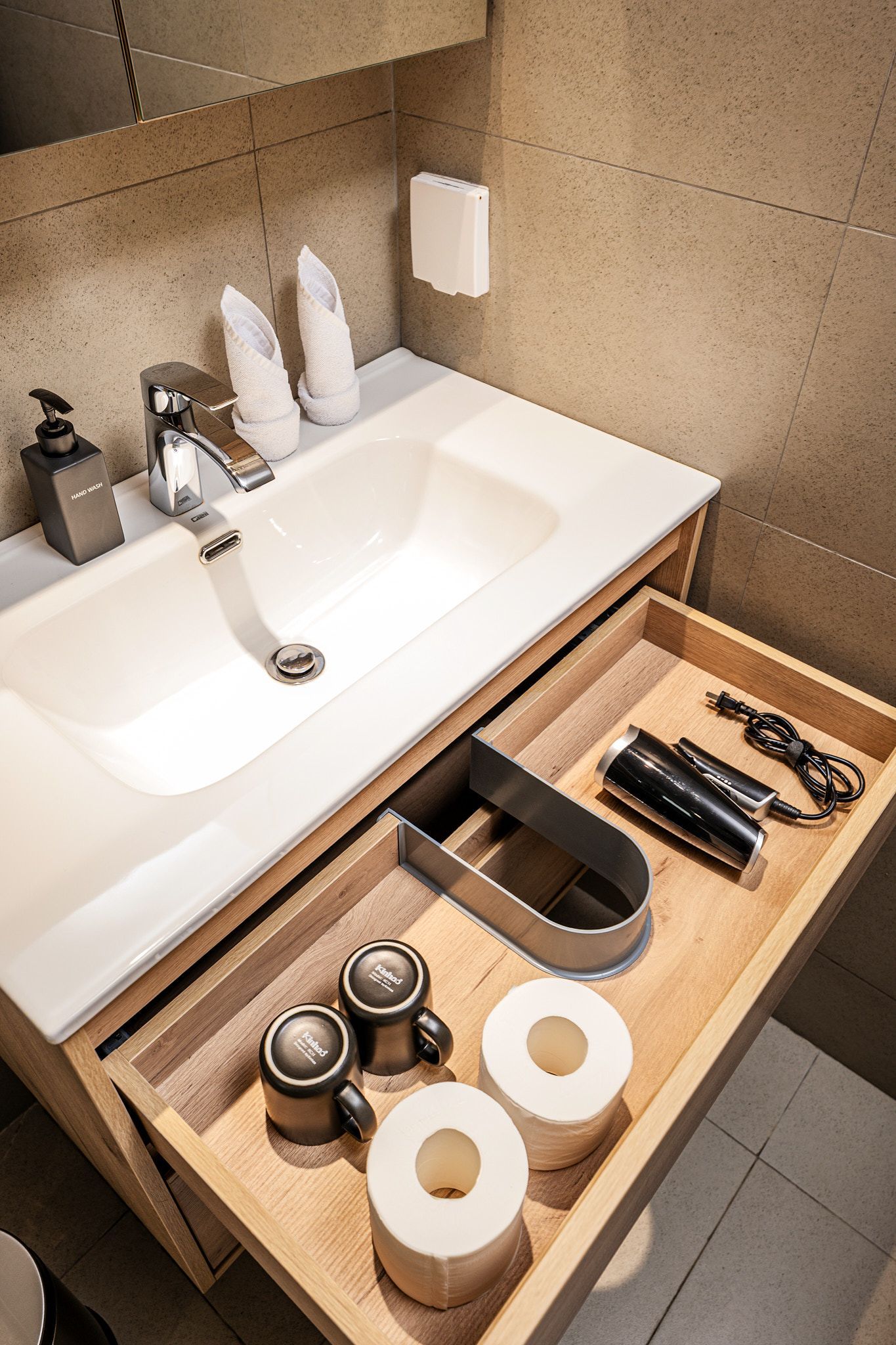 Bathroom vanity with sink and an open drawer holding toiletries and grooming items
