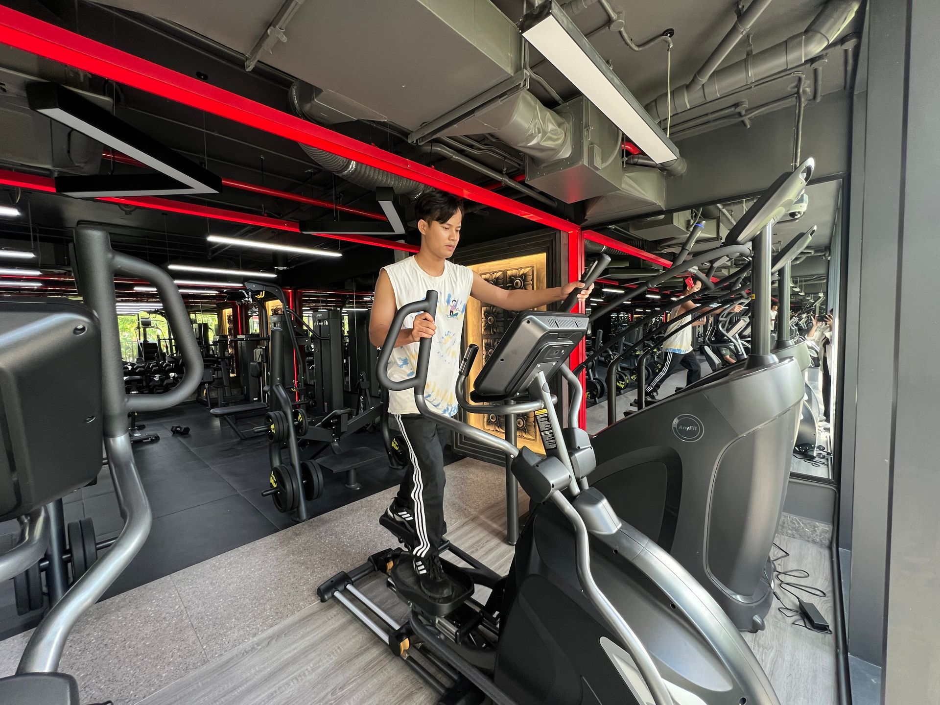 Row of treadmills in a gym; various fitness equipment visible in the background.