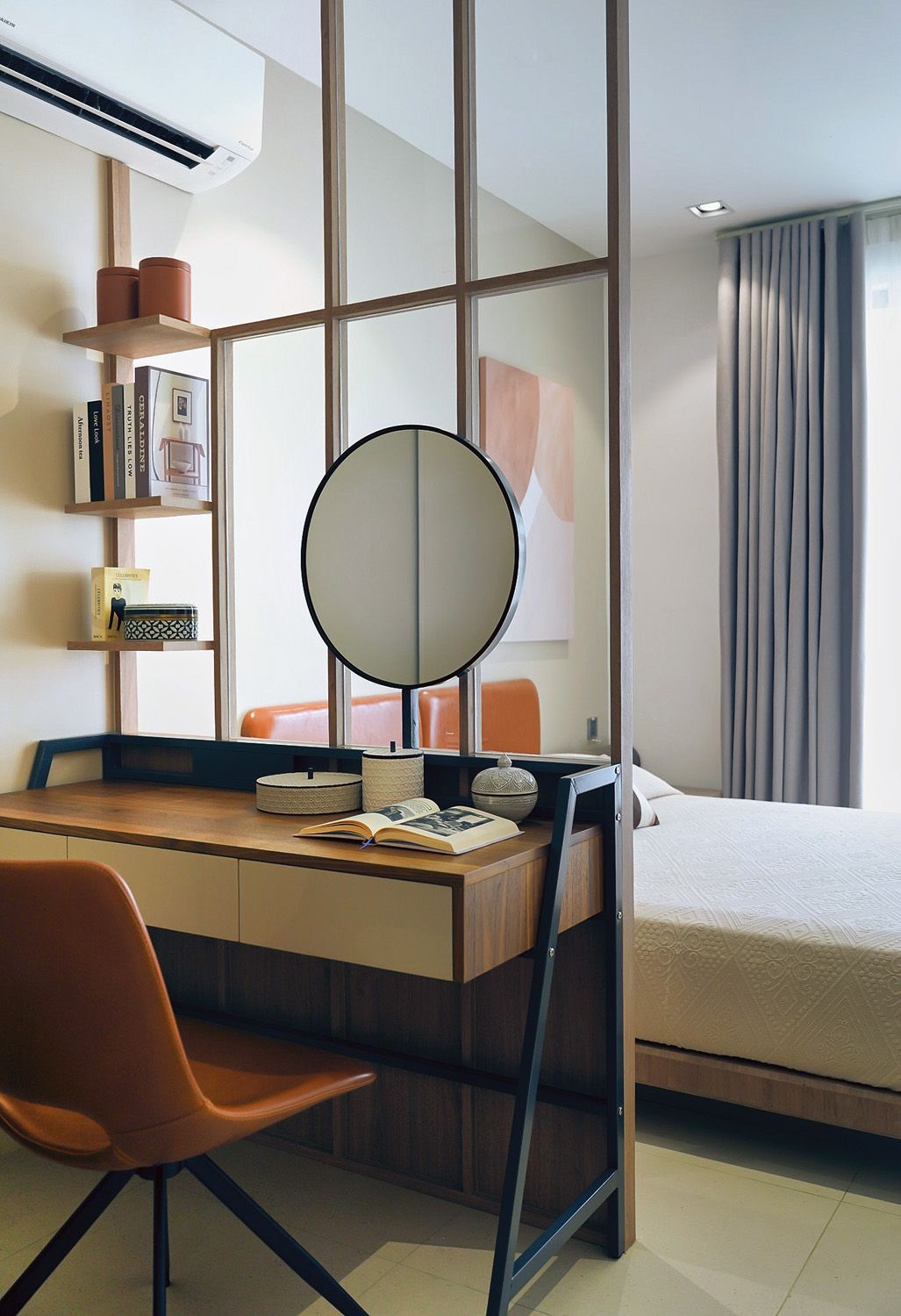 Modern bedroom with a desk, chair, round mirror, and bed beside a window with curtains.