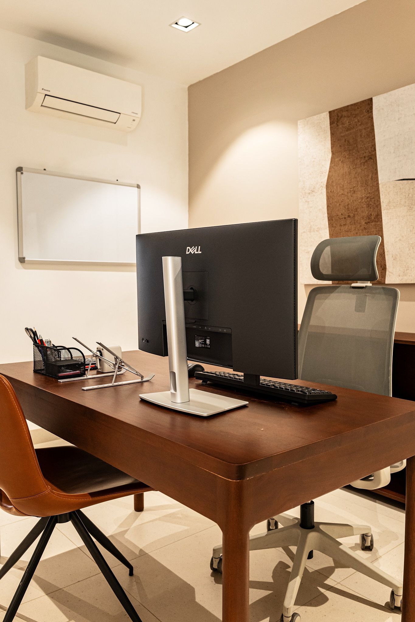 Modern office with wooden desk, computer monitor, chair, whiteboard, and air conditioner on the wall